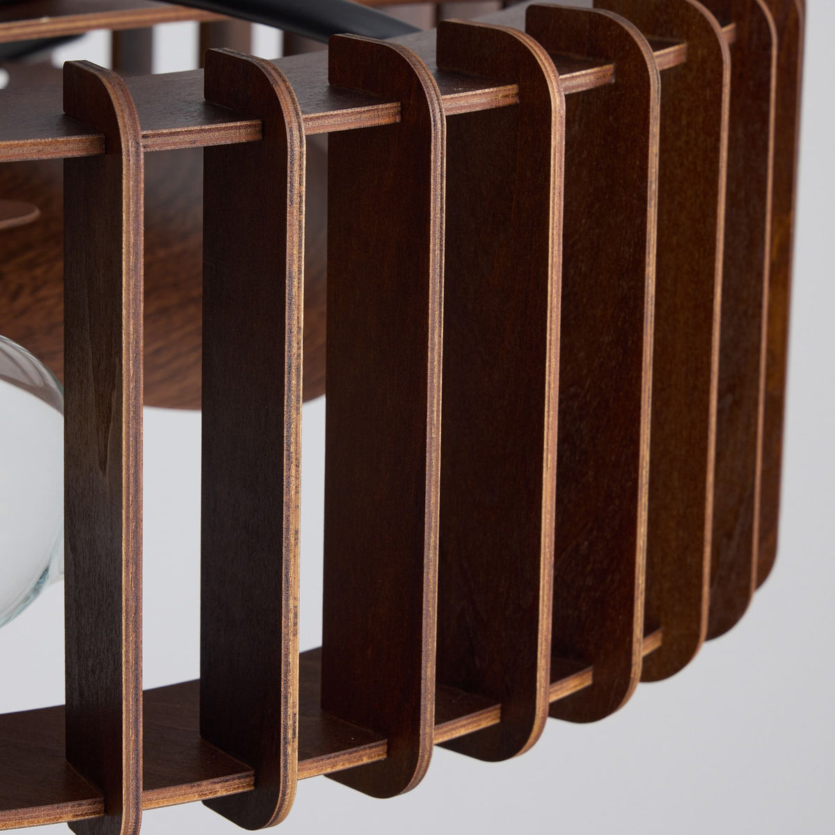 Close-up of industrial caged fan wooden slat structure — dark wood vertical bars, curved top and bottom rails, layered plywood edge grain, flush mount ceiling plate detail | Sofary Lighting