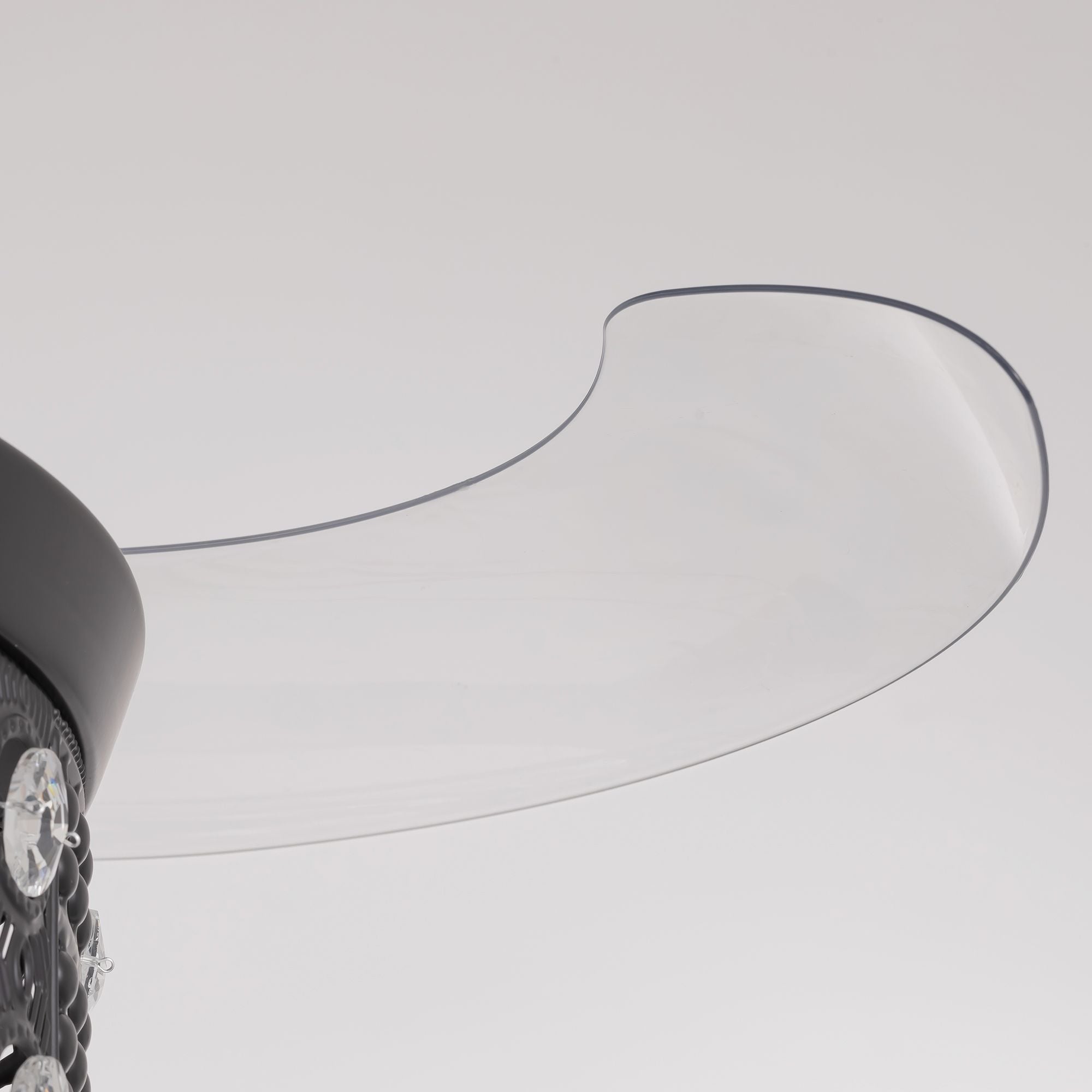 Close-up of retractable fan blade — transparent curved acrylic blade with dark edge trim, extended from black center hub, invisible blade design detail | Sofary Lighting