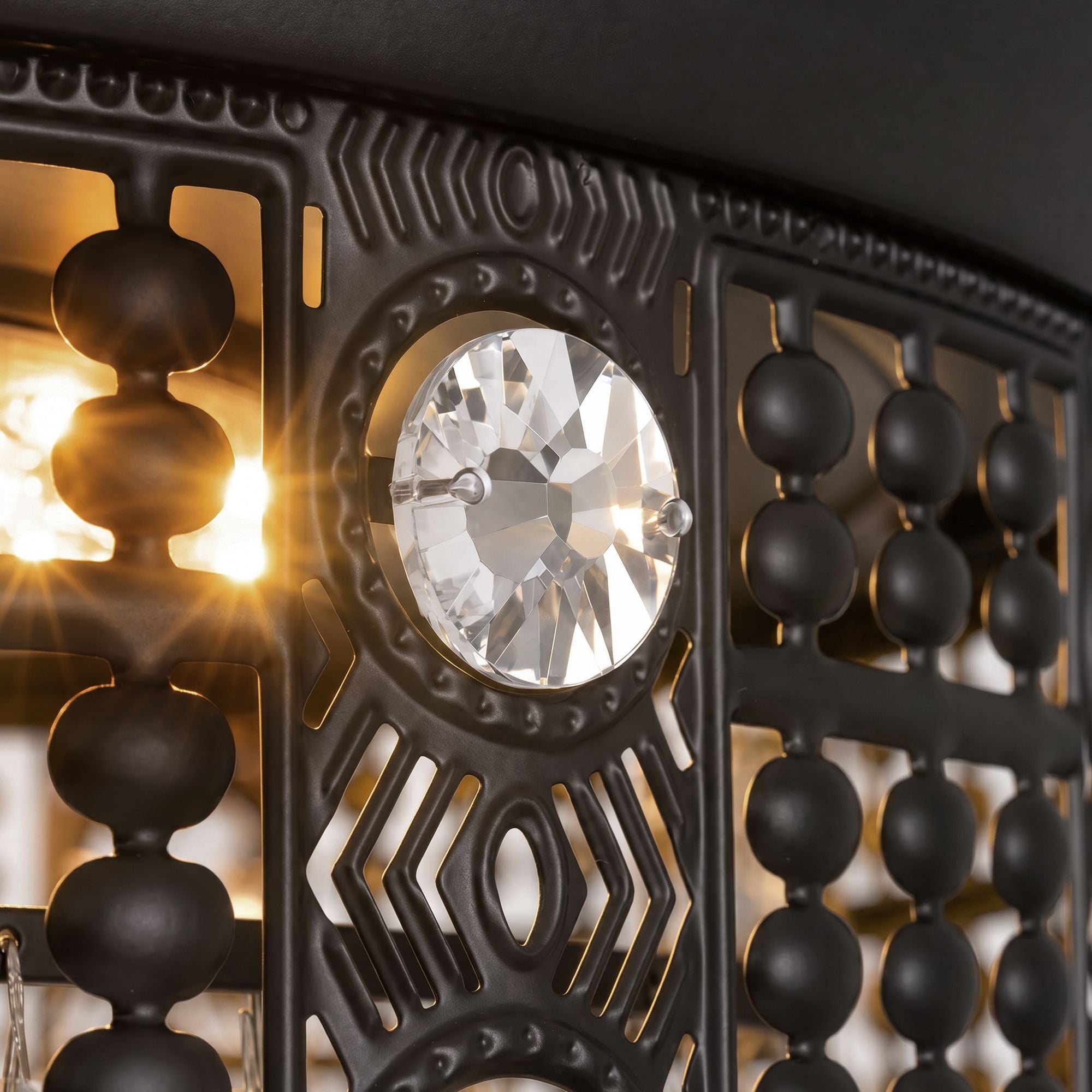 Close-up of ceiling fan canopy and LED light — black ornate metalwork with geometric cutouts, central crystal jewel, beaded crystal trim, warm LED starburst glow | Sofary Lighting