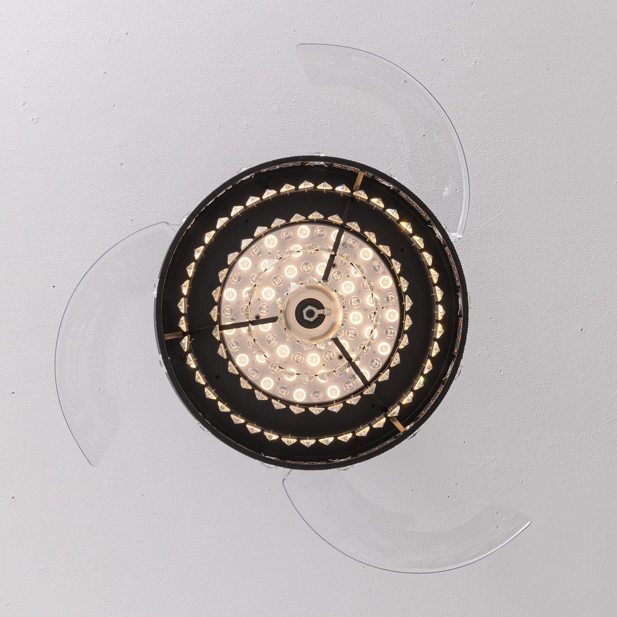 Top-down view of 48" black crystal retractable ceiling fan — transparent blades fully extended, central LED light ring, black radial frame, flush mount to ceiling | Sofary Lighting