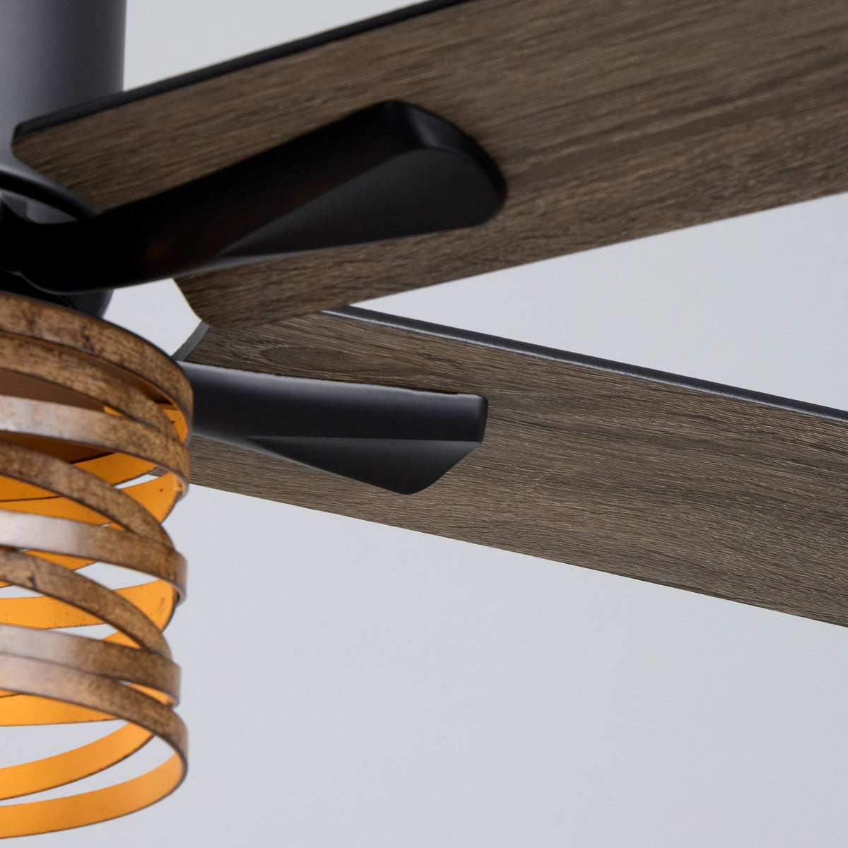 Close-up of 52" industrial farmhouse ceiling fan — wood grain reversible blade with black bracket and motor arm, amber ribbed glass light shade edge, matte black hardware, craftsmanship detail | Sofary Lighting