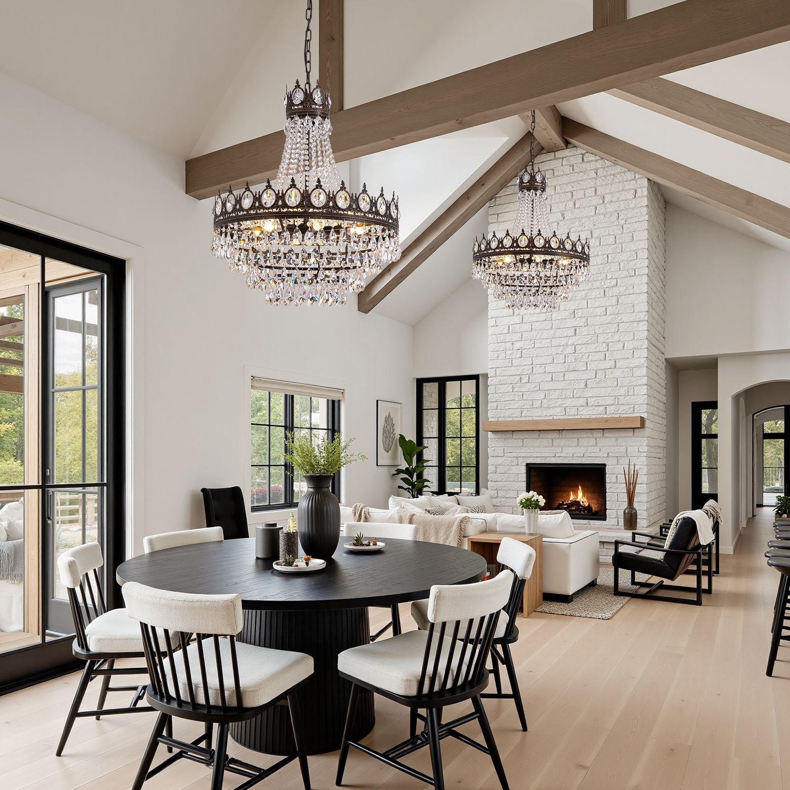 Aerian Crystal Chandelier in modern farmhouse dining room — vaulted ceiling, exposed wood beams, round black table, twin fixtures over fireplace living space | Sofary Lighting