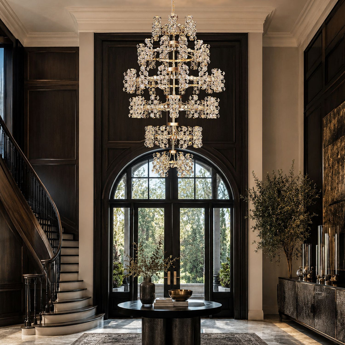 Aeriol Grand Chandelier in luxury entryway — dark wood floors, arched glass doors, curved staircase, round table with florals, dramatic crystal cascade welcomes guests with opulence | Sofary Lighting