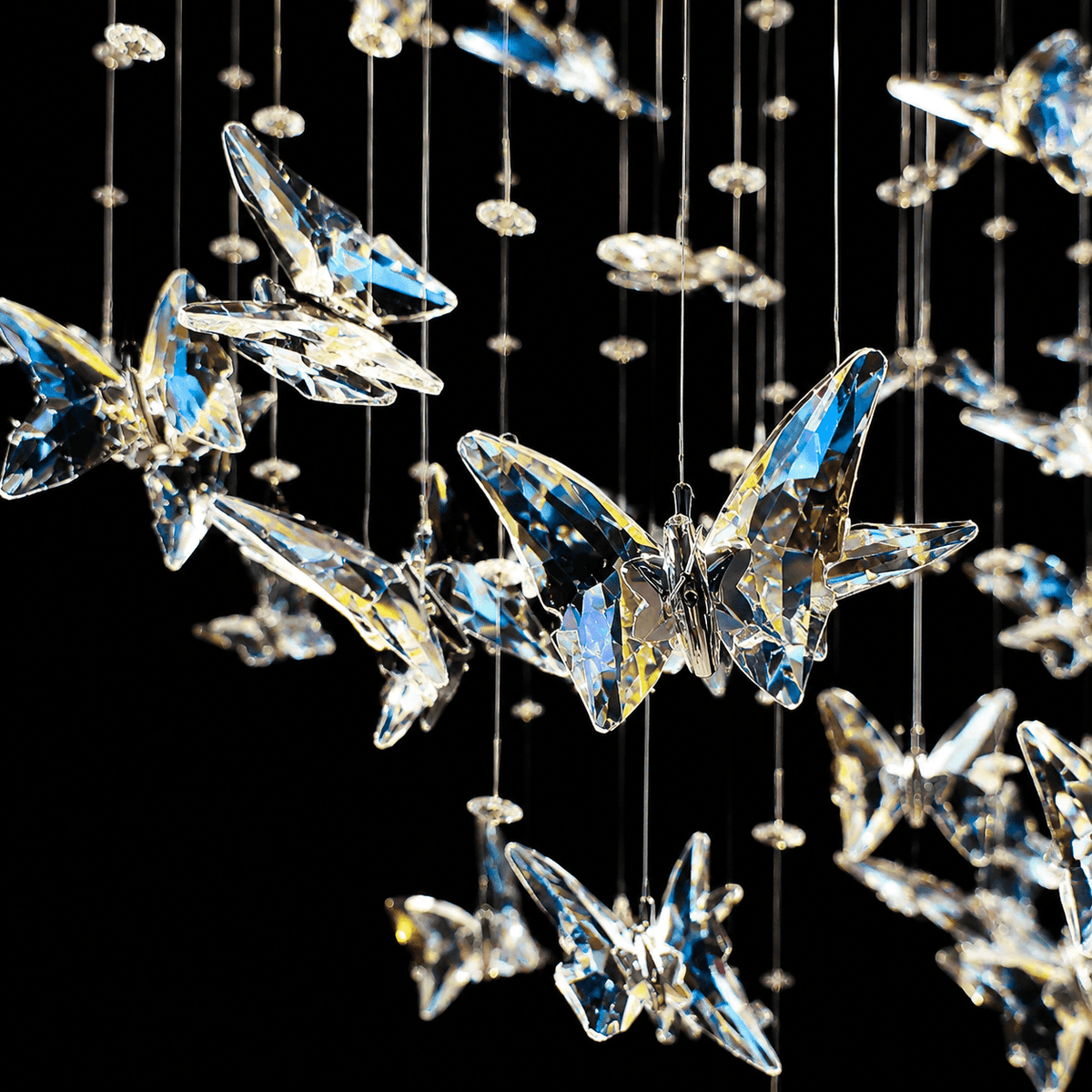 Close-up of Aeris chandelier — faceted K9 crystal butterfly wings, gold connector, light refraction and iridescent sparkle, dark background | Sofary Lighting