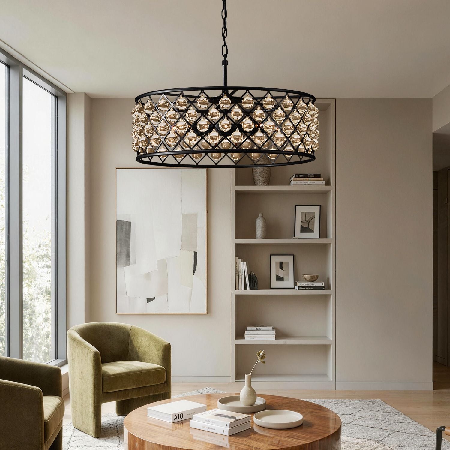 Harlow Vintage Matte Black K9 Crystal Round Chandelier in a living room — suspended above a beige sofa with decorative pillows, a light-colored coffee table, and a bookshelf backdrop | Sofary Lighting