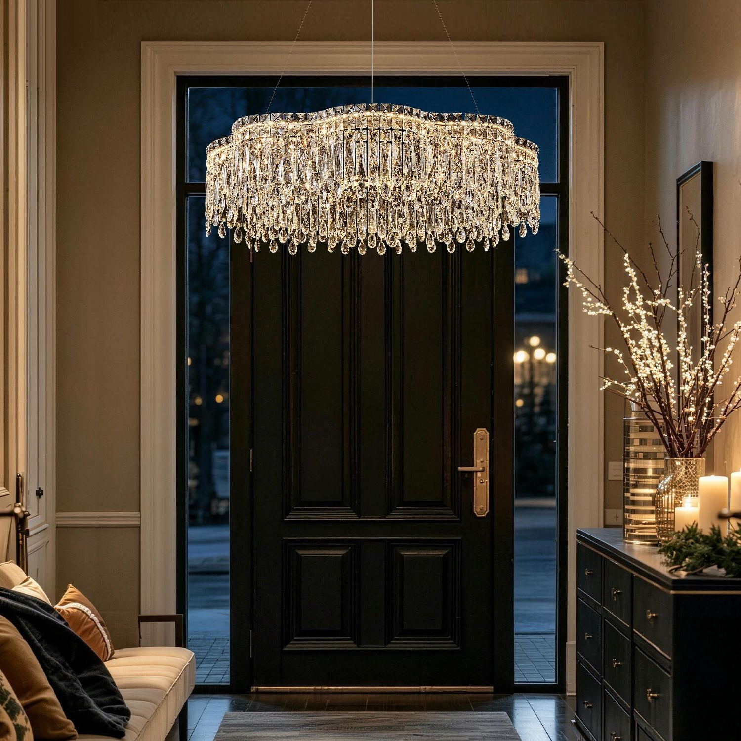Luna Modern Wave Integrated LED K9 Crystal Ring Chandelier in a foyer — hanging above a dark wood front door with a black console table, flowers, and candles | Sofary Lighting