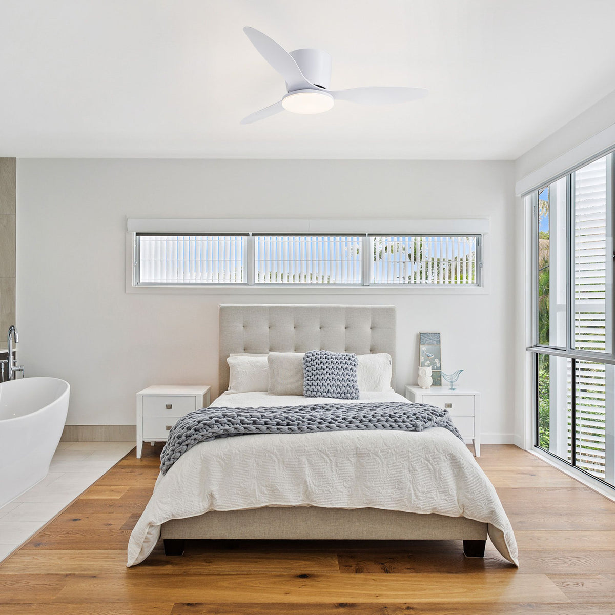 White flush mount ceiling fan in bedroom — beige tufted bed, wooden floor, bright windows, modern minimalist bedroom decor | Sofary Lighting
