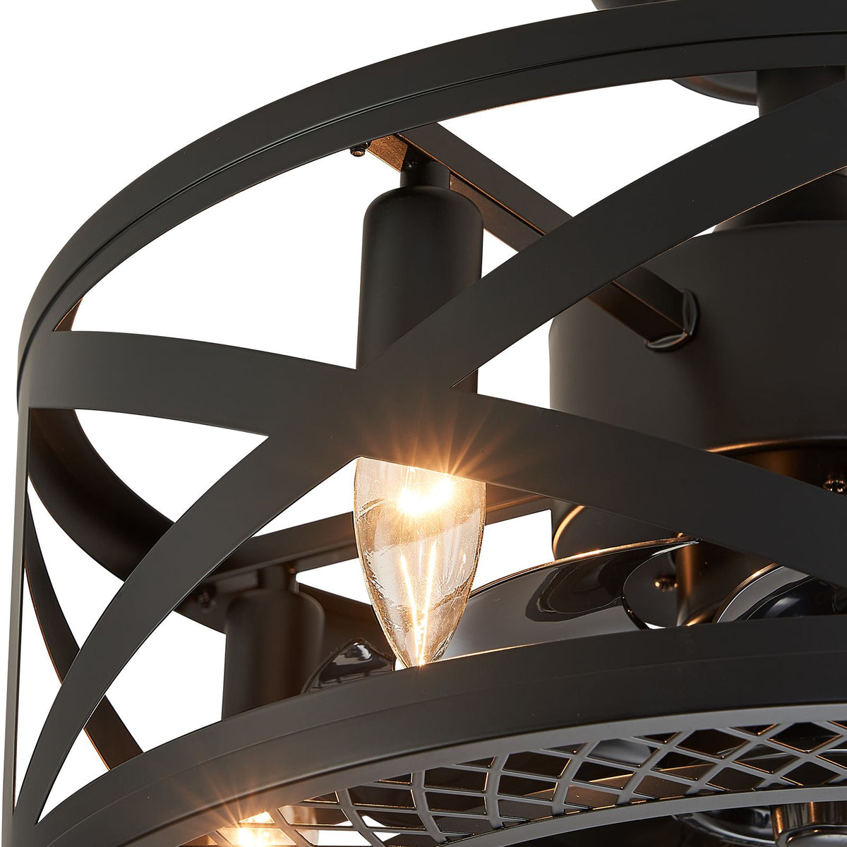 Close-up of industrial caged fan — vintage E12-style bulb glow, crisscross matte black metal frame, warm light reflection | Sofary Lighting