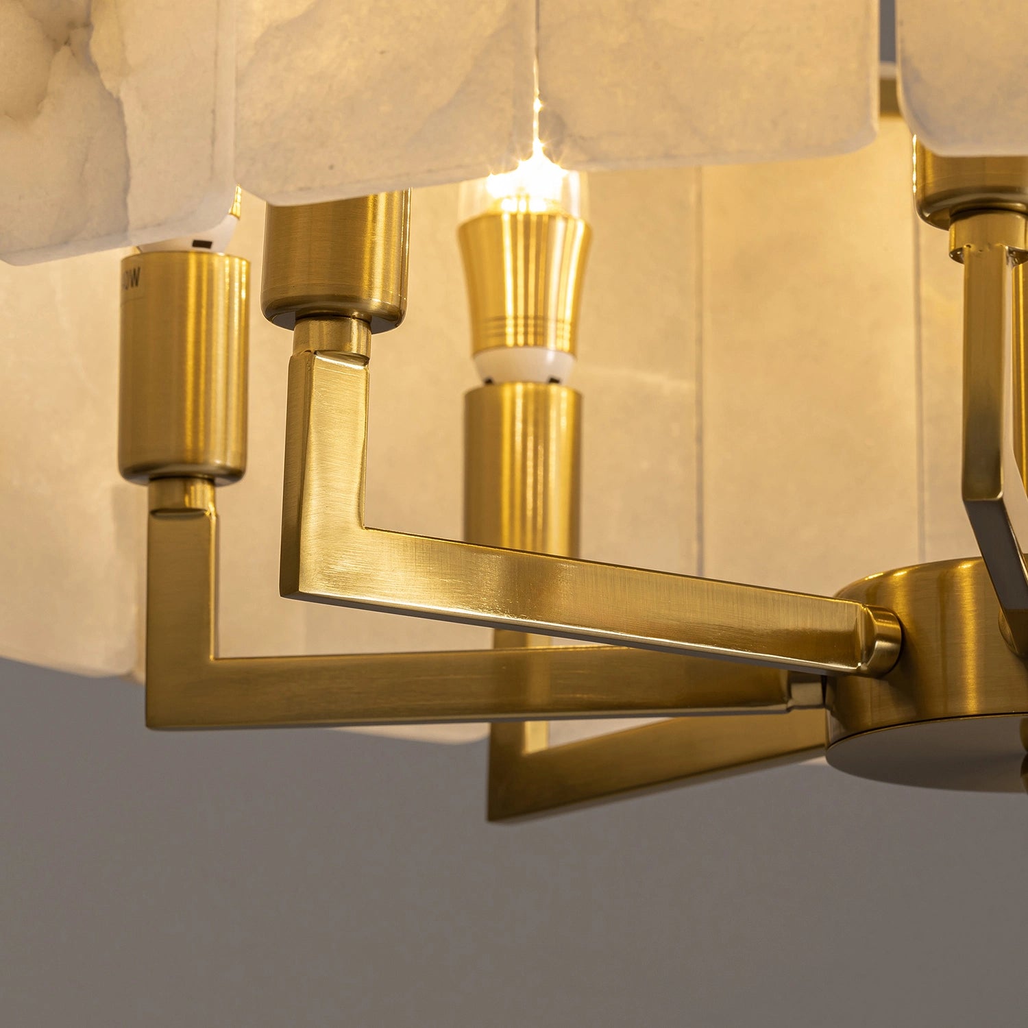 High-angle view of a circular alabaster stone chandelier showcasing the gold frame detail in a modern high-ceiling living room. Sofary Lighting