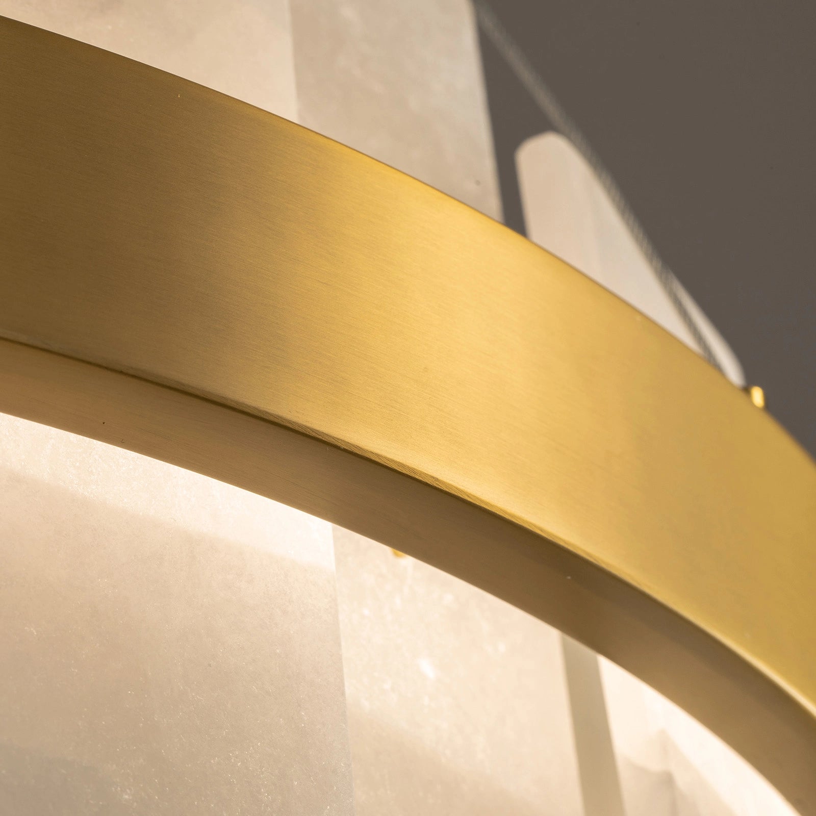 close-up-of-modern-round-alabaster-gold-chandelier-with-circular-gold-frame-and-evenly-spaced-alabaster-panels-emitting-warm-light-sofary-lighting