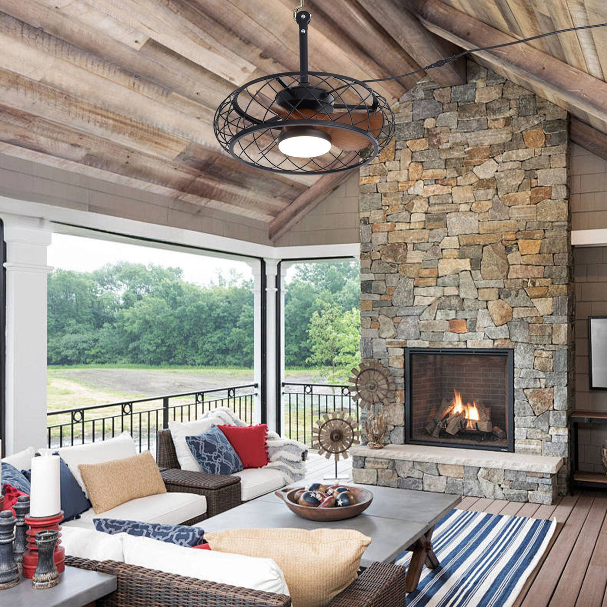 Caged ceiling fan in covered patio — stone fireplace, wood beam ceiling, outdoor sofa, rustic industrial outdoor lighting & fan | Sofary Lighting