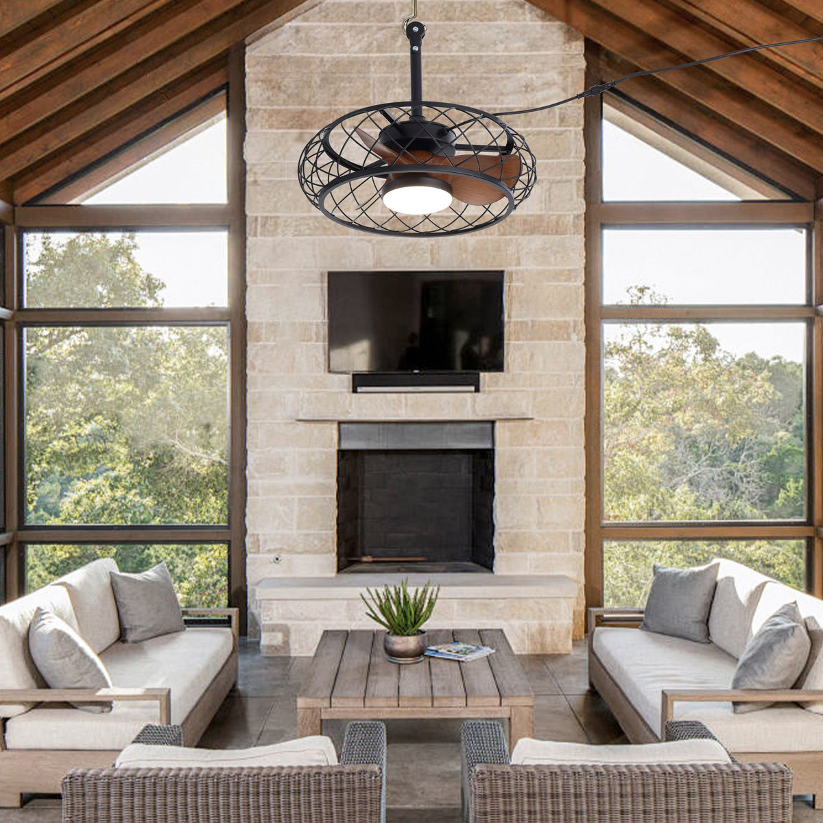 Caged ceiling fan in enclosed patio — stone fireplace, mounted TV, wood vaulted ceiling, wicker furniture, waterproof plug-in fan for indoor-outdoor living | Sofary Lighting