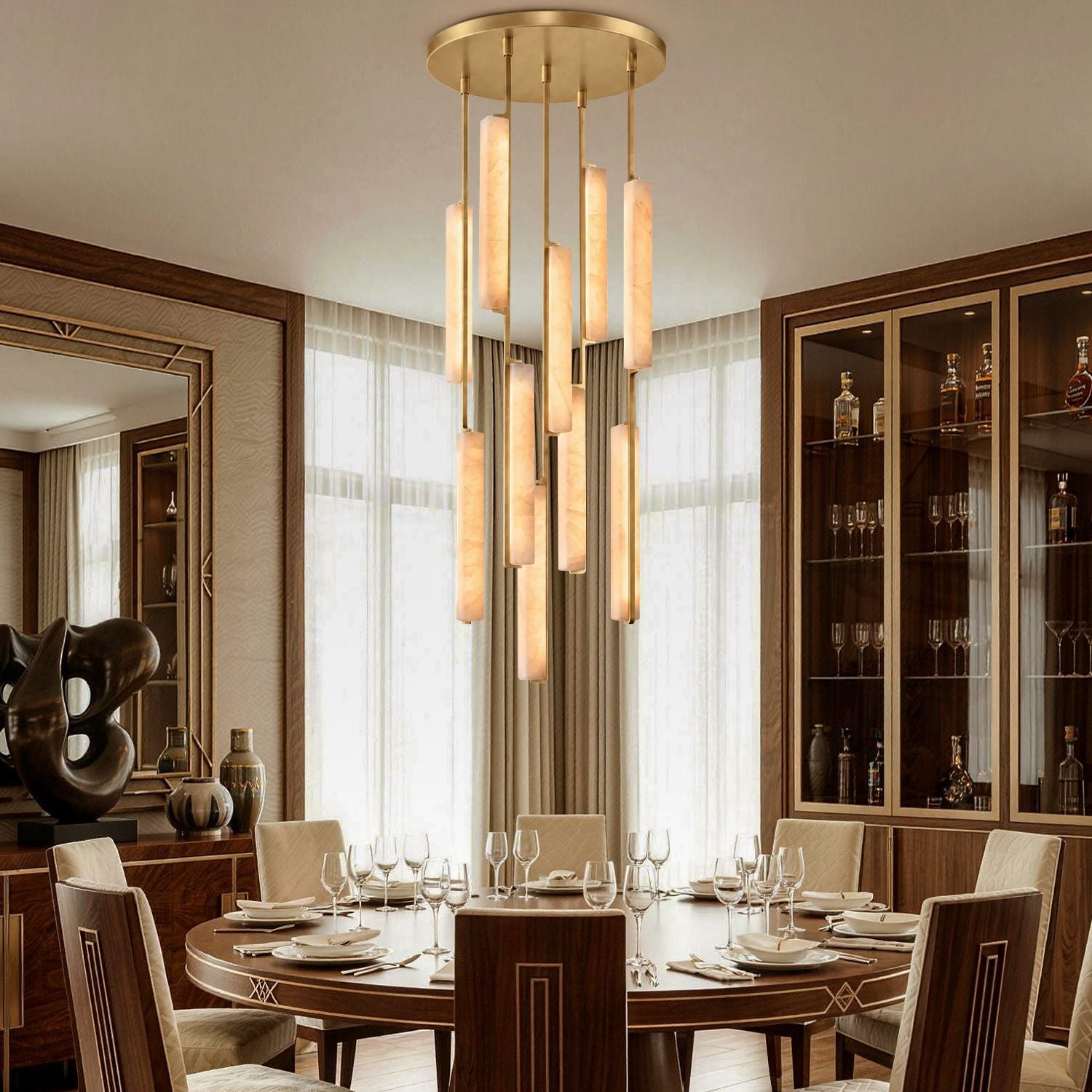 Stamen Modern Minimalist Alabaster Vertical Chandelier in a dining room — hanging above a round wooden table set for fine dining, with glass cabinets and elegant tableware in the background