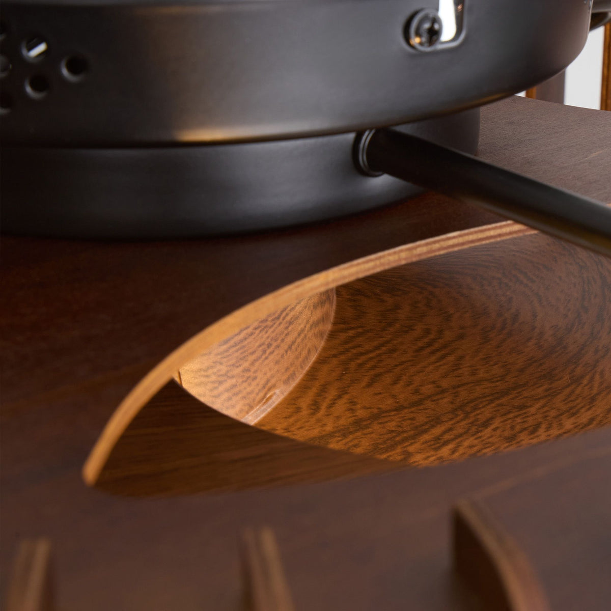 Close-up of industrial caged fan motor and blade joint — matte black metal motor housing with screws and vent holes, dark wood grain blade with curved upturned edge, black bracket arm, premium craftsmanship detail | Sofary Lighting