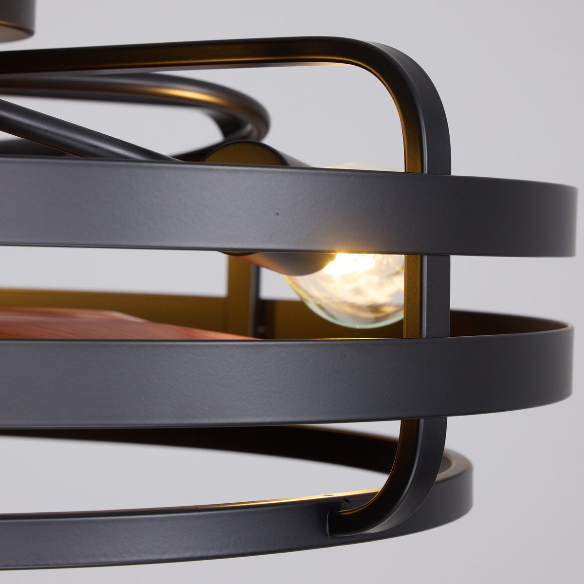 Black and gold caged frame detail — matte black metal rings, gold inner accents, warm glowing filament bulb, industrial farmhouse craftsmanship | Sofary Lighting