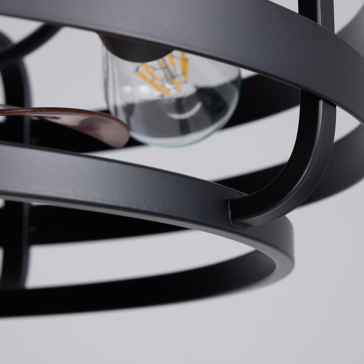 Exposed E26 filament bulb detail — matte black cage frame, smooth metal finish, vintage bulb glow, modern caged fandelier close-up | Sofary Lighting