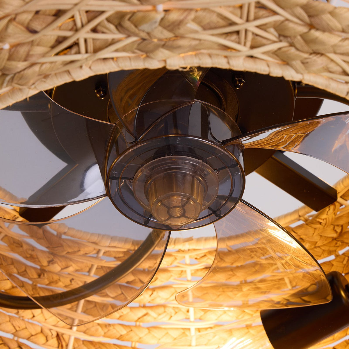 Close-up of boho rattan ceiling fan — woven rattan shade, transparent smoked blades, black motor housing, warm LED light detail | Sofary Lighting