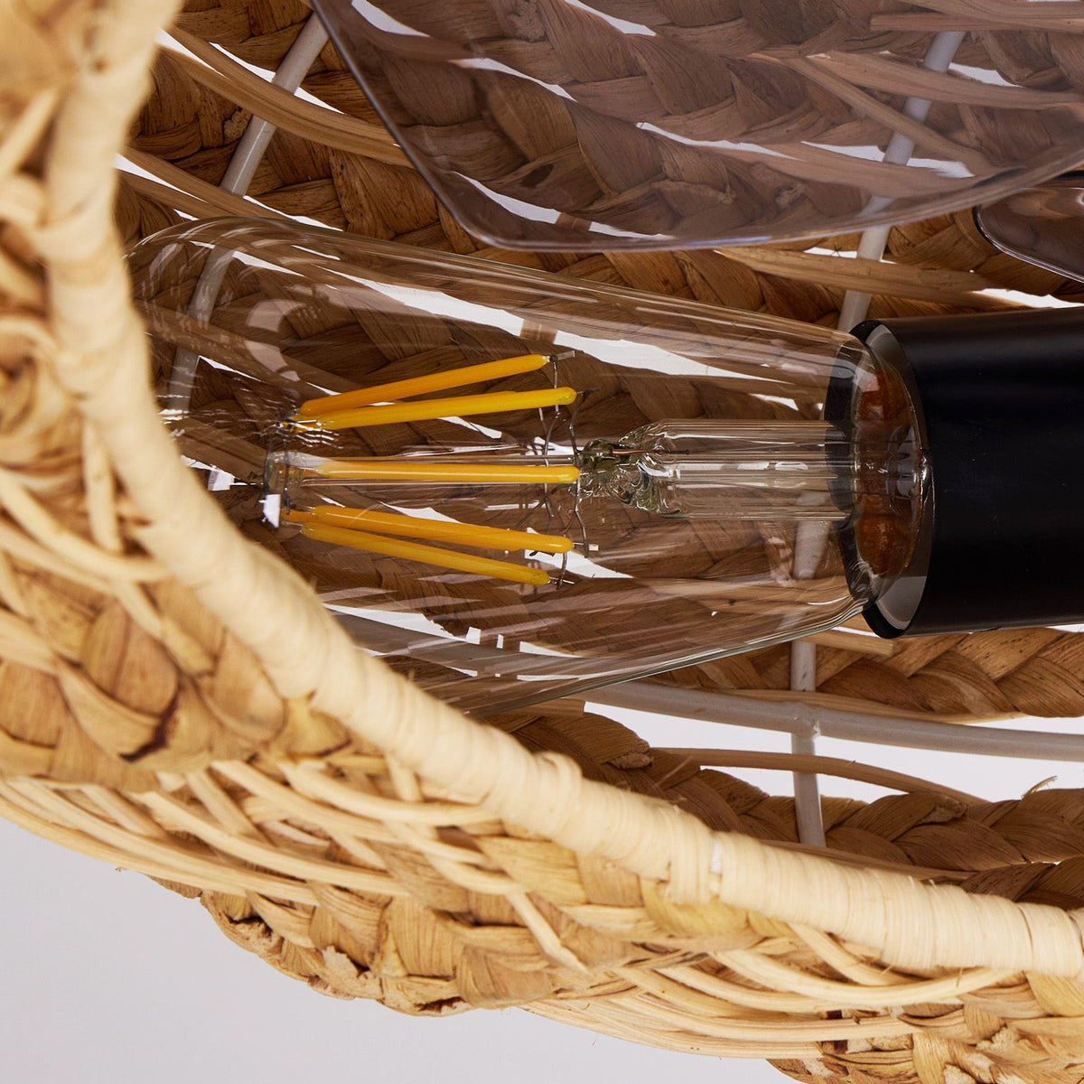Close-up of rattan fan light bulb — clear LED filament bulb, warm yellow glow, black socket, woven rattan edge, vintage boho lighting detail | Sofary Lighting
