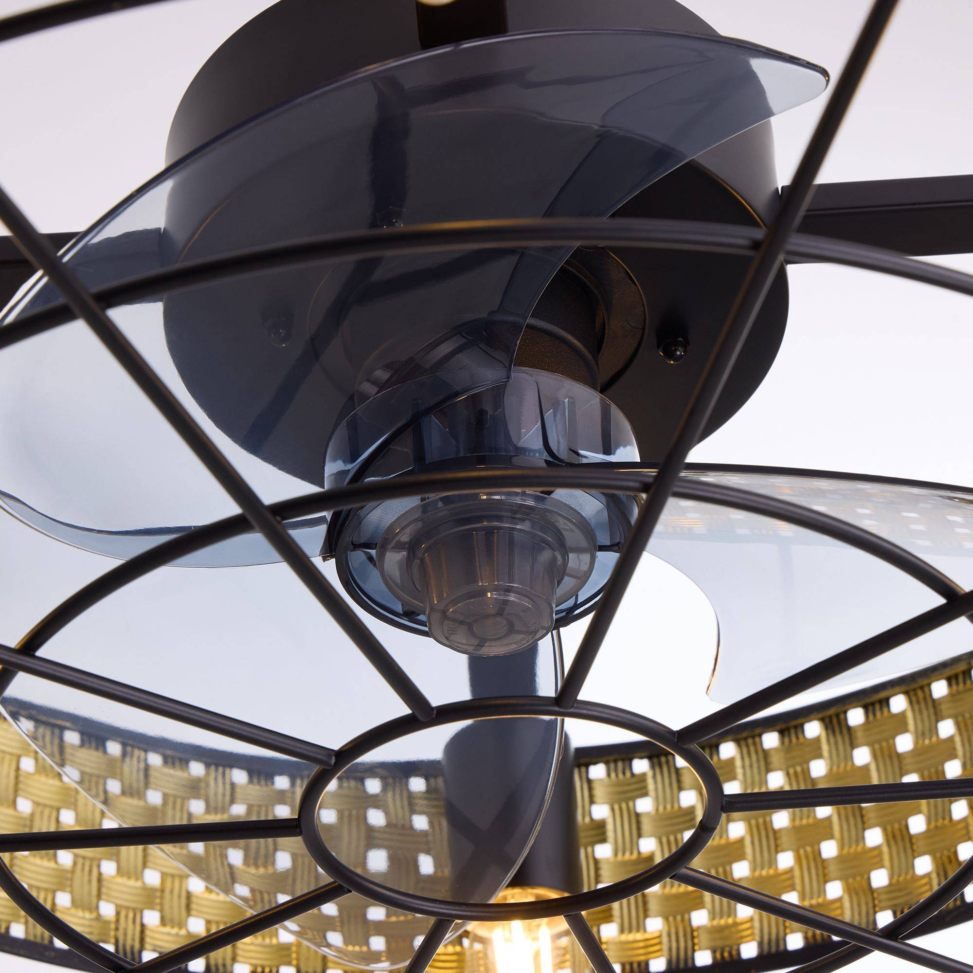 Close-up of boho rattan ceiling fan blades and motor — translucent enclosed blades, matte black motor housing, wire cage, vintage Edison bulb glow, woven rattan shade | Sofary Lighting