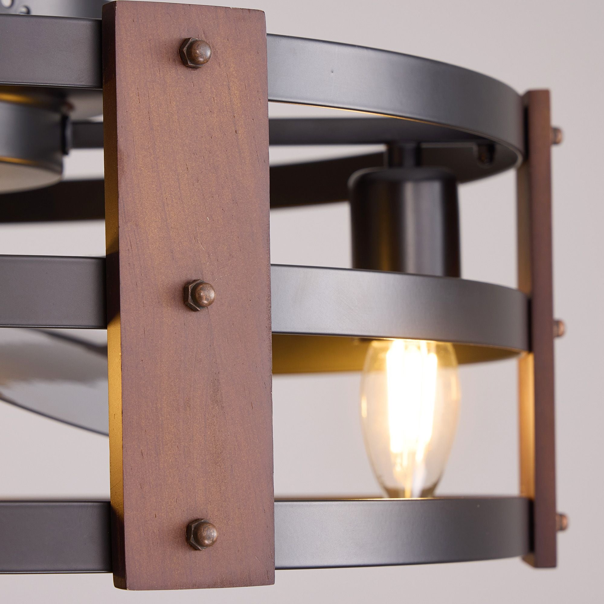 Close-up of rustic wood panel with metal rivets and vintage Edison bulb — matte black cage, warm glow, industrial farmhouse craftsmanship detail | Sofary Lighting