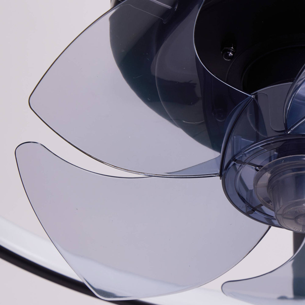 Close-up of smart ceiling fan blades — transparent smoked gray ABS blades, curved aerodynamic design, black central motor housing, quiet enclosed fan