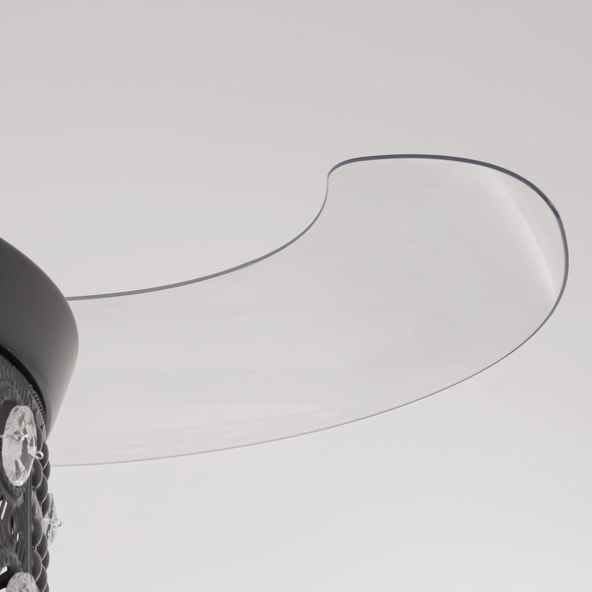 Close-up of retractable fan blade — transparent curved acrylic blade with dark edge trim, extended from black center hub, invisible blade design detail | Sofary Lighting