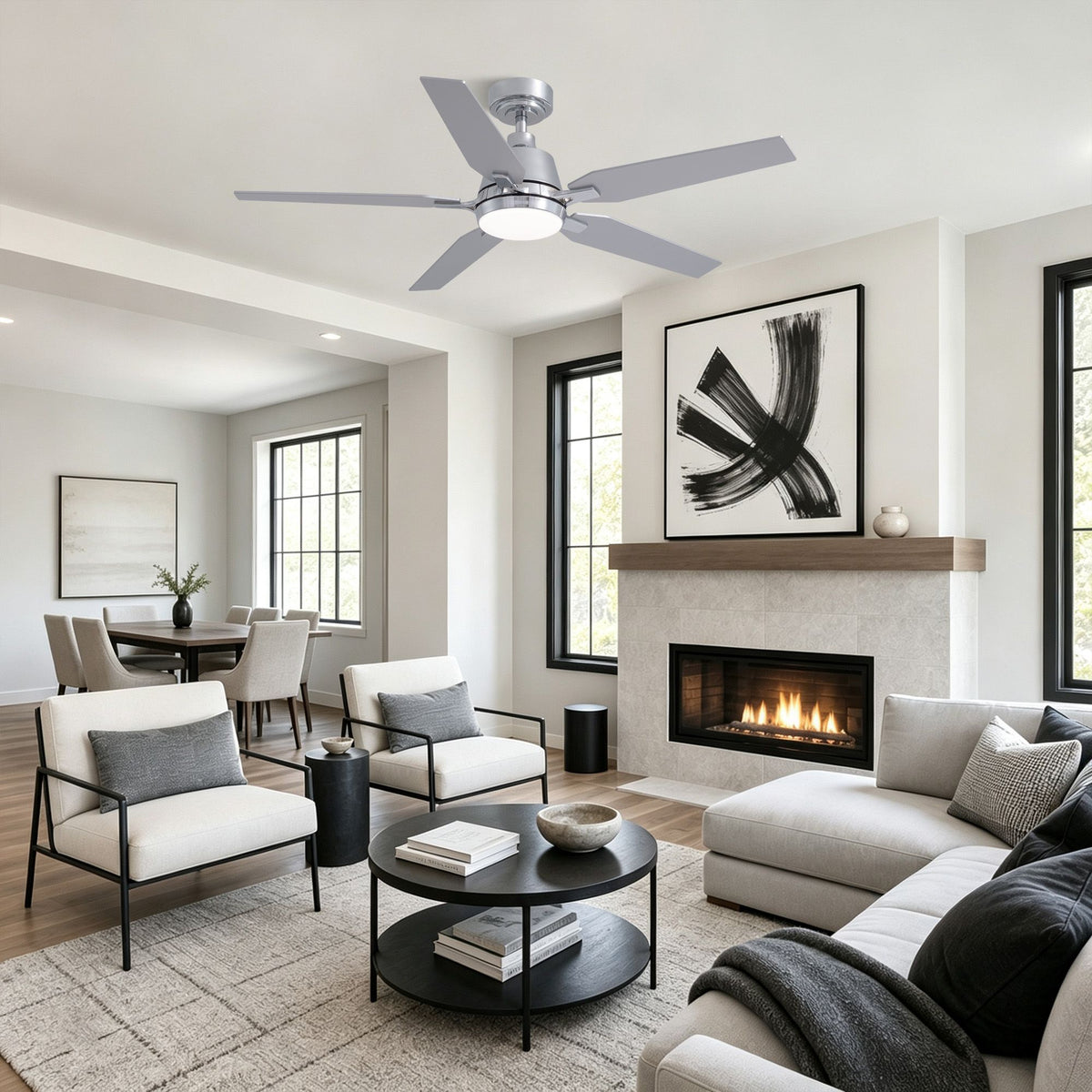 Chrome ceiling fan in open living room — L-shaped sofa, white armchairs, fireplace, abstract art, bright modern home decor