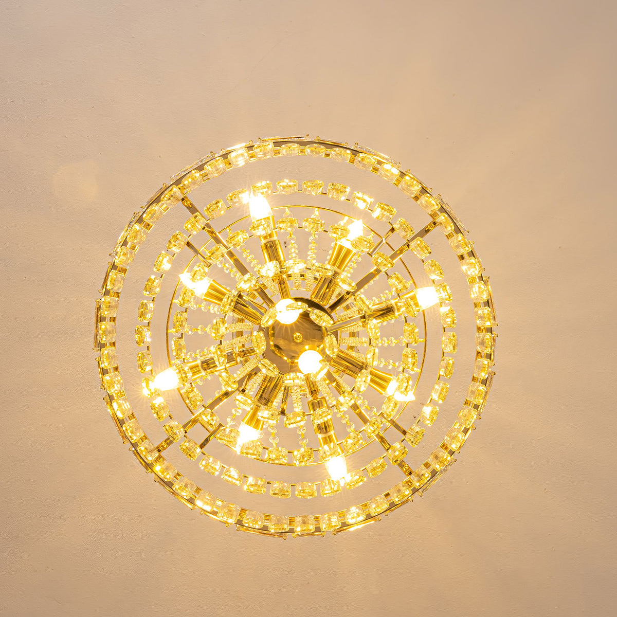 Aeros Empire Gold Crystal Chandelier bottom view — circular tiered crystal rings, glowing candle-style lights, gold center canopy, installed on ceiling, radial symmetry | Sofary Lighting