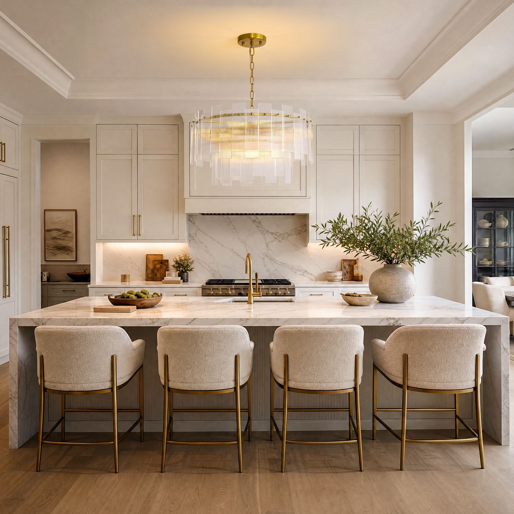 Aerosel Brass Glass Chandelier over modern kitchen island — white cabinets, marble countertop, beige upholstered stools, gold fixtures | Sofary Lighting