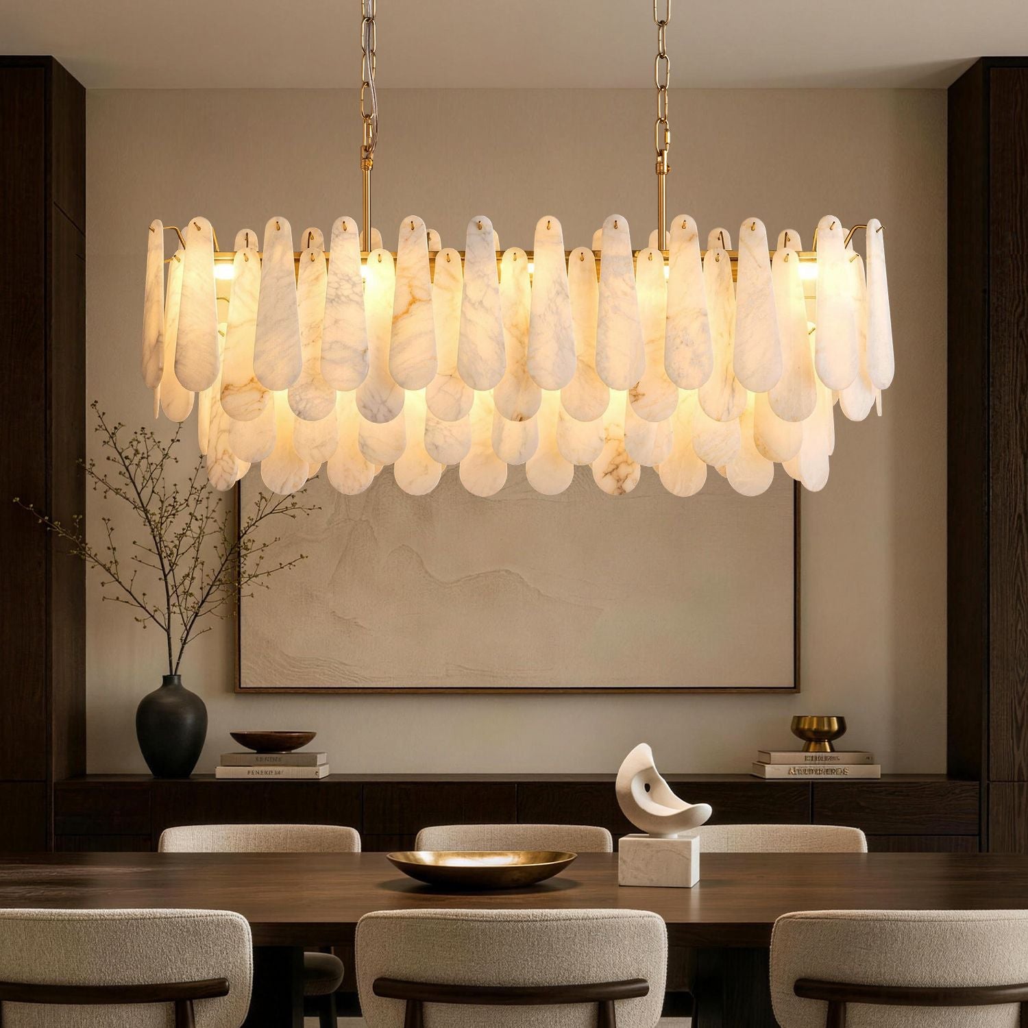 Apex Modern Minimalist Alabaster Linear Chandelier in a sophisticated dining room — featuring a rectangular frame with layered alabaster stone pendants, suspended above a dark wood table set with a golden bowl and a vase of white flowers, against a beige wall with abstract art | Sofary Lighting