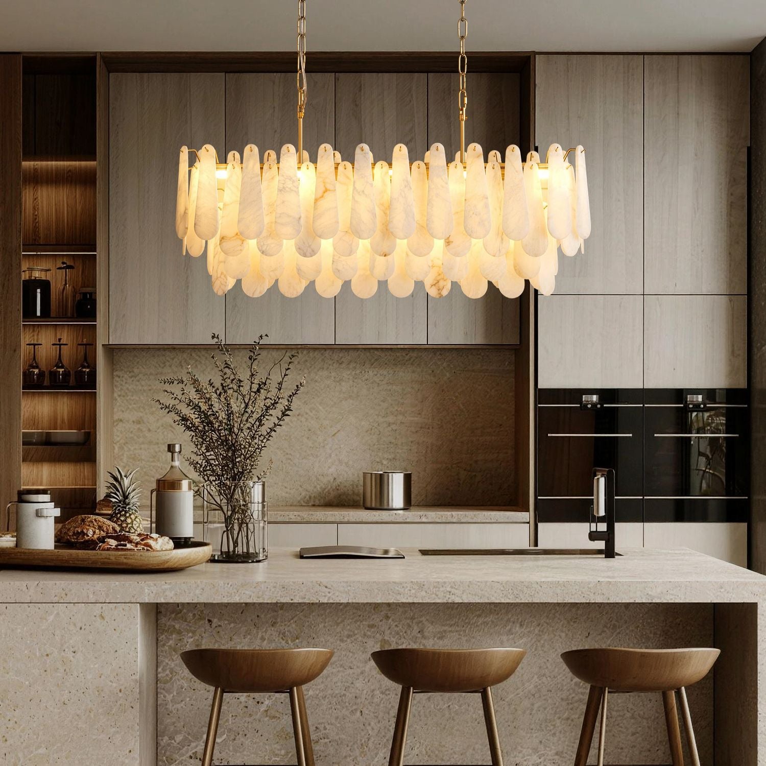 Apex Modern Minimalist Alabaster Linear Chandelier hanging above a modern kitchen island — paired with light wood cabinetry, marble countertop, and minimalist decor including a pineapple and glass vases | Sofary Lighting