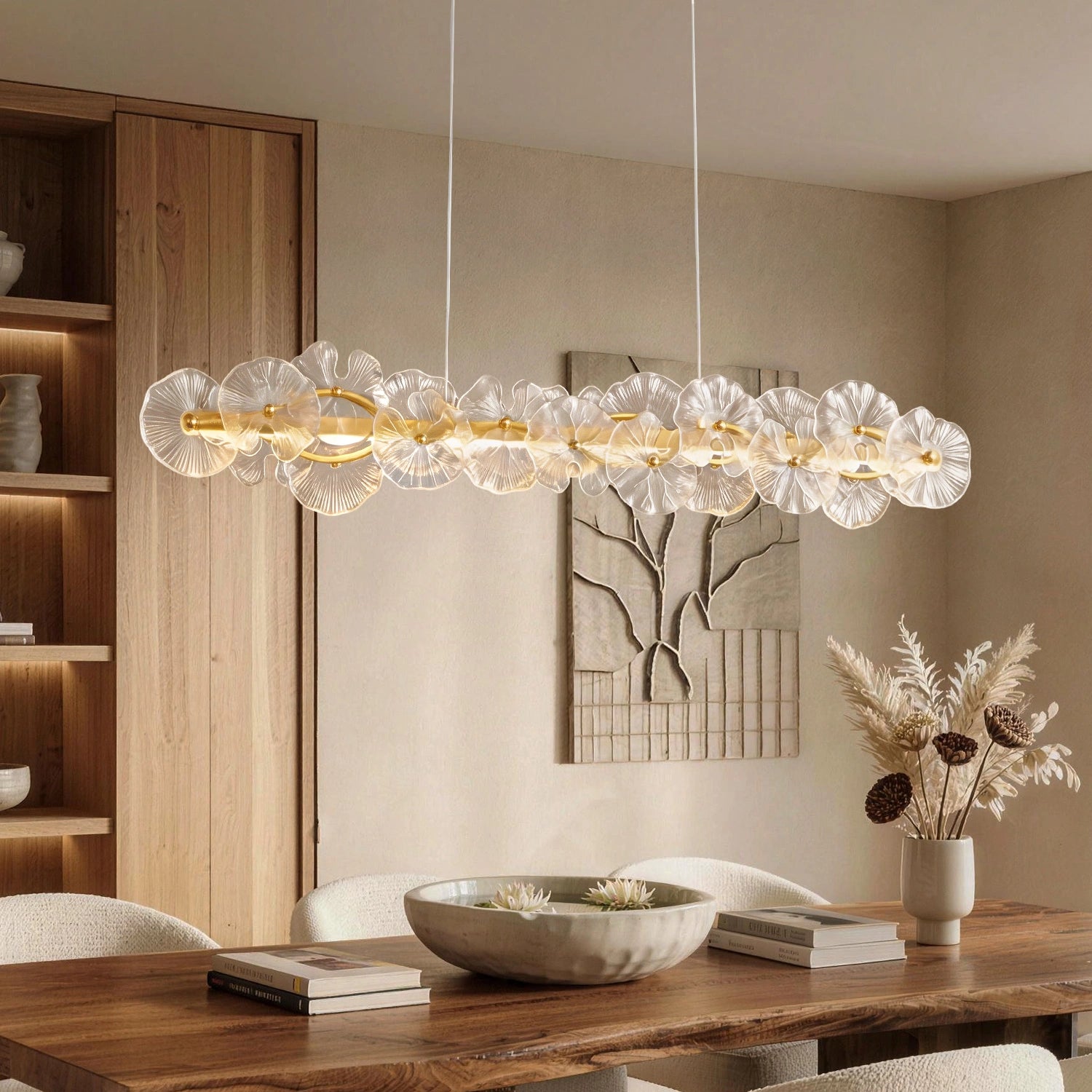 Contemporary Linear Glass Flower Chandelier with textured petals and a gold frame suspended over a rustic wooden dining table in a minimalist room. Sofary Lighting