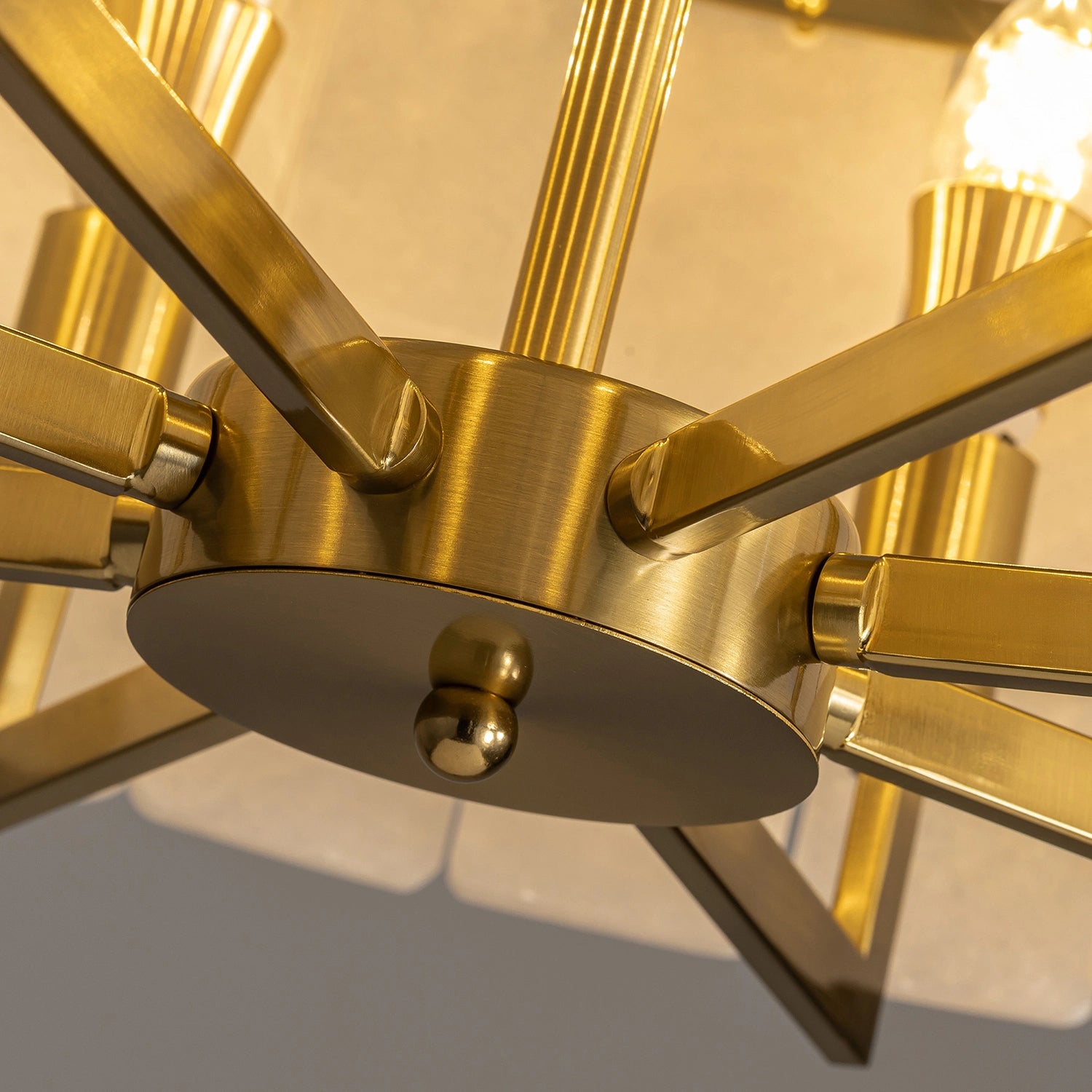 Macro view of the brushed gold brass central hub and structural arms of a round chandelier, showcasing premium metal finish and durable construction. Sofary Lighting
