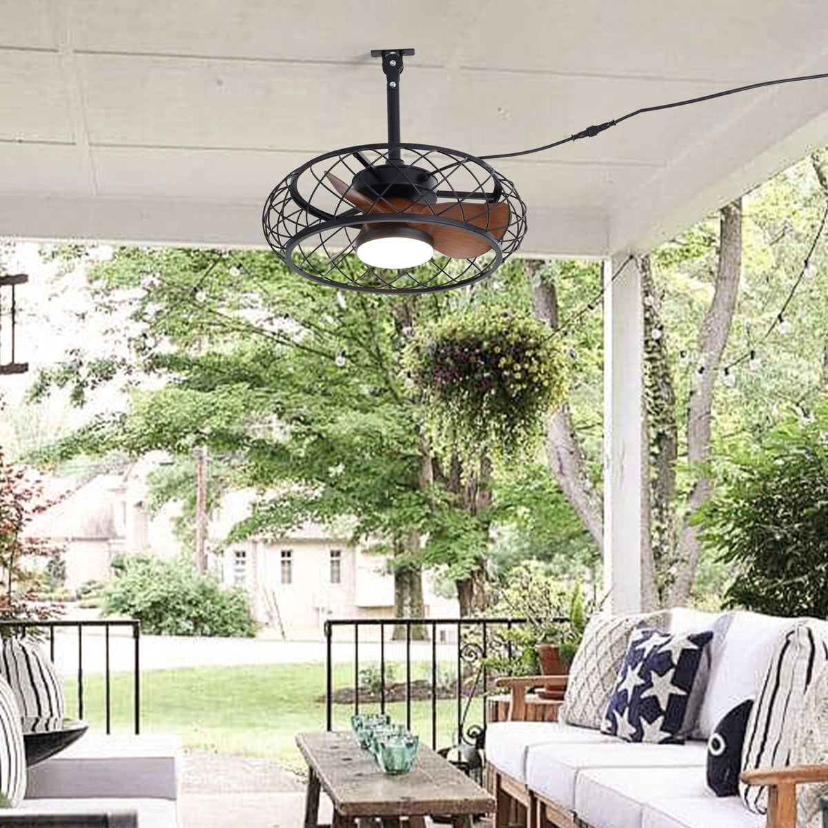 Caged ceiling fan on backyard patio — outdoor sofa, hanging plants, trees background, plug-in cord, waterproof outdoor fan with light | Sofary Lighting
