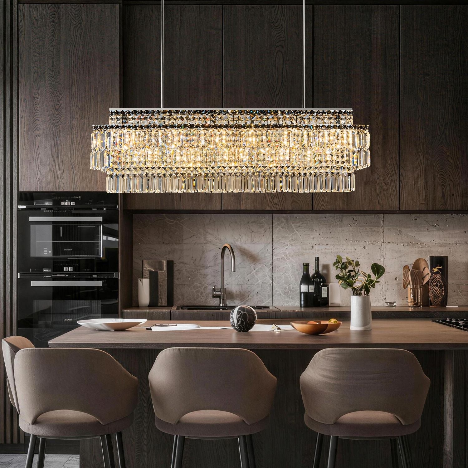 Stellar Grand Linear Silver Multi-Faceted K9 Crystal Chandelier in a kitchen island — suspended above a wooden countertop with dark cabinets, a marble backsplash, and kitchen utensils | Sofary Lighting
